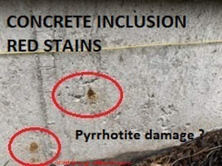 Red stain from inclusion in a concrete foundation - is this pyrrhotite? (C) InspectApedia.com ML