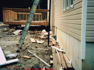 Construction debris dumped around the building foundation wall (C) Daniel Friedman at InspectApedia.com