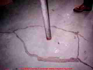 Photograph of a settlement crack in a basement floor around a Lally column pier.