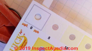 Arsenic in water test strip being read against the color chart (C) Daniel Friedman at InspectApedia.com